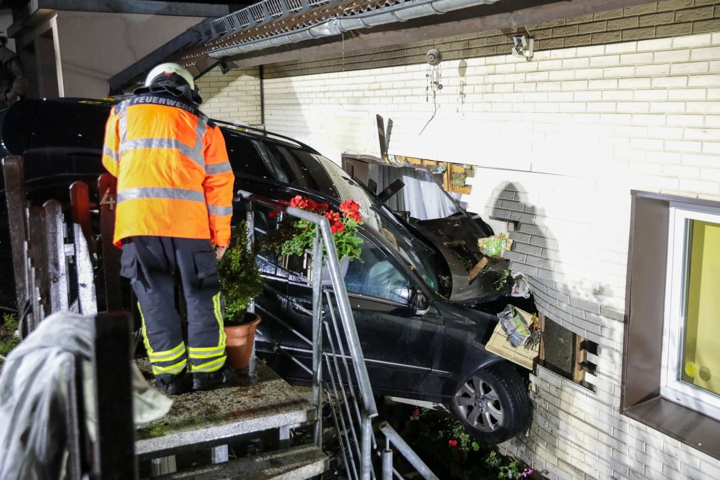 Rettungskräfte inspizieren das Auto, das in Wuppertal die Wand eines Wohnhauses durchbrochen hat.
