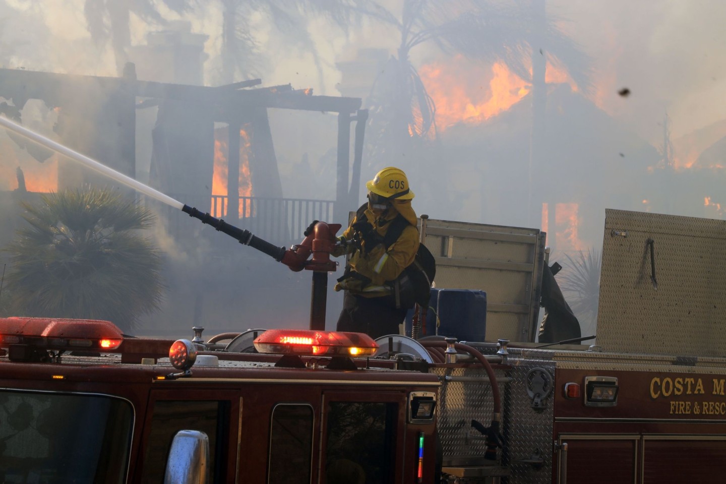 Ein Feuerwehrmann vom Costa Mesa Fire Department löscht in Laguna Niguel ein Haus, das während eines Lauffeuers in Brand geraten ist.