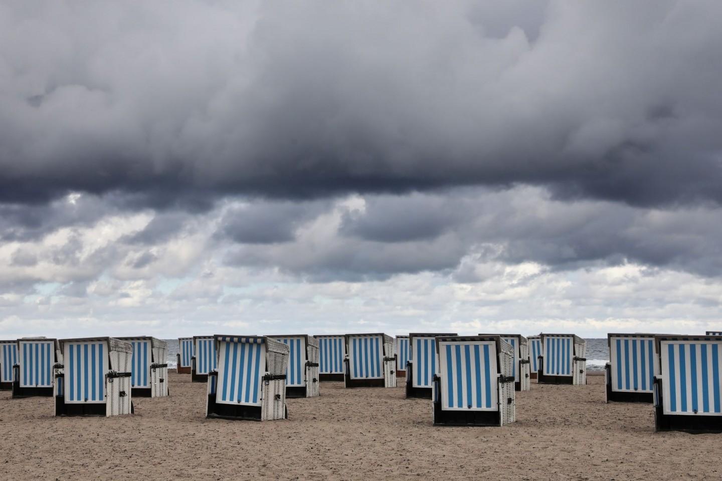 Dunkle Wolken ziehen über den Ostseestrand von Warnemünde. Sommerliches Wetter ist vorerst nicht in Sicht.