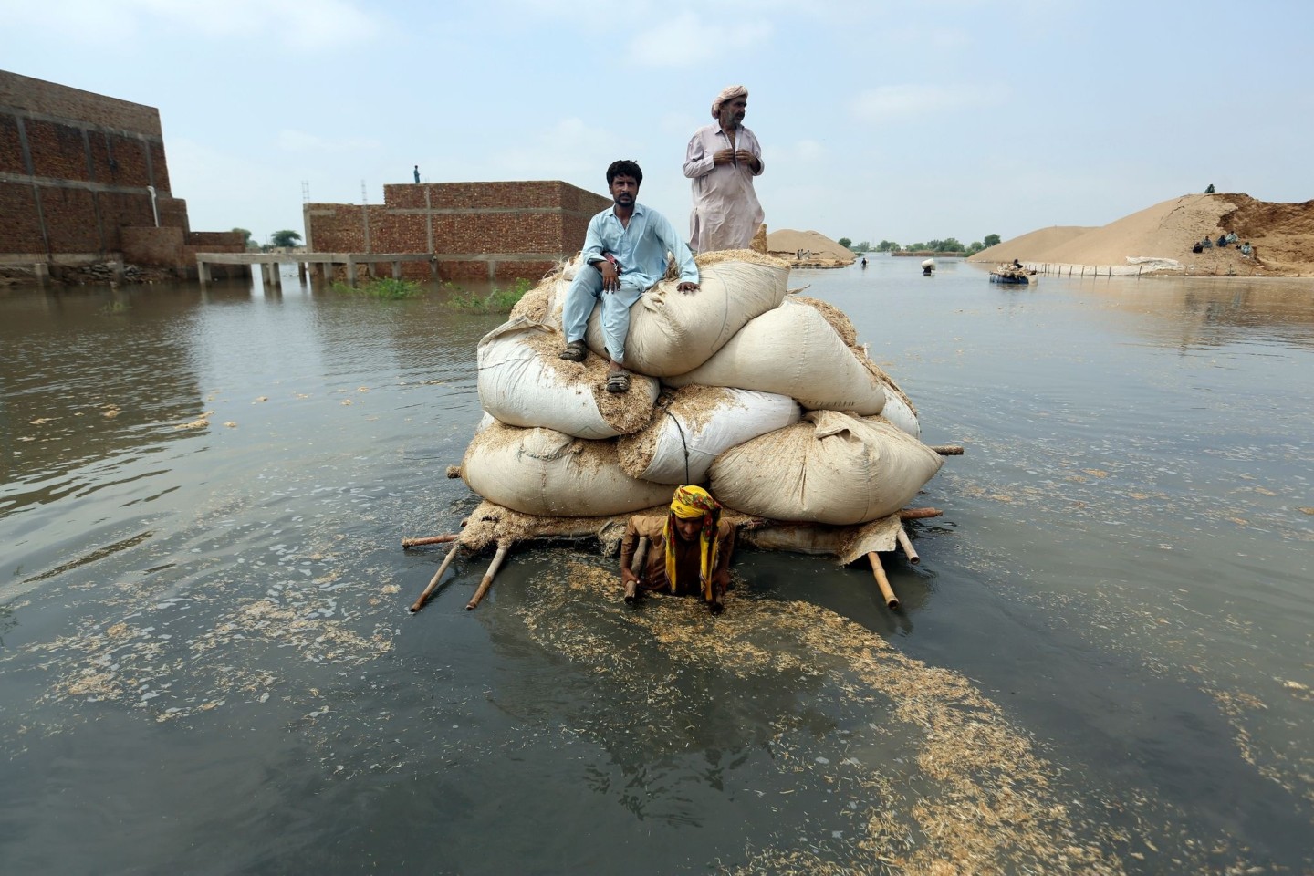 Opfer der Überschwemmungen benutzen einen behelfsmäßigen Lastkahn, um Heu für das Vieh zu transportieren.
