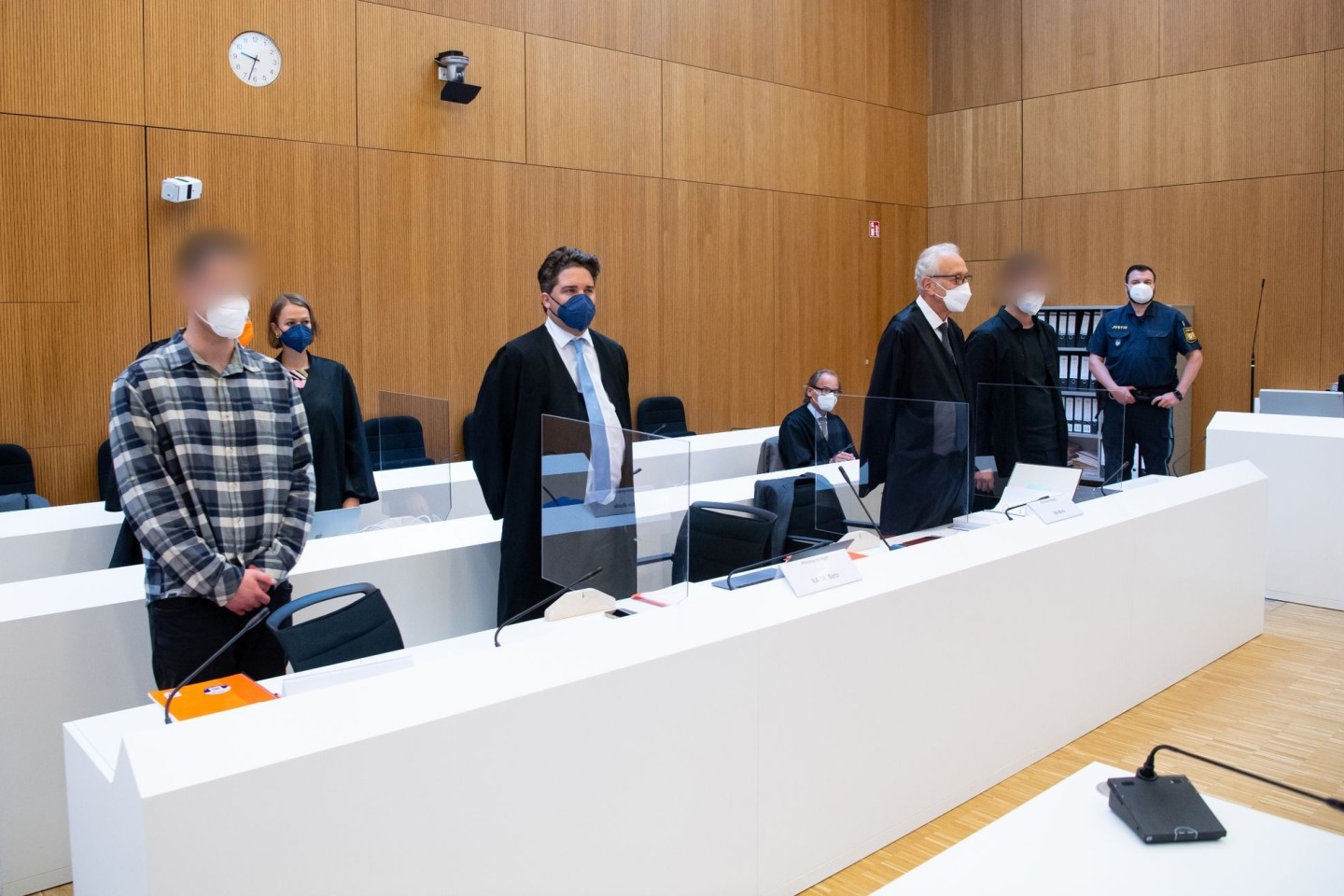 Die zwei wegen Mordes angeklagten Männer (l und 2.v.r.) mit ihren Anwälten vor Beginn der Verhandlung im Sitzungssaal.