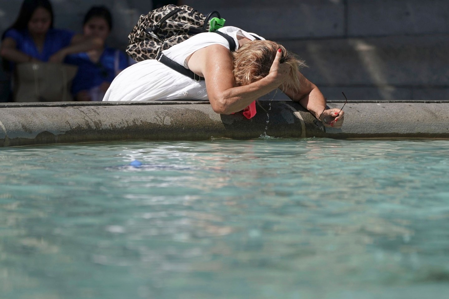 Eine Frau erfrischt sich an einem Brunnen auf dem Trafalgar Square.