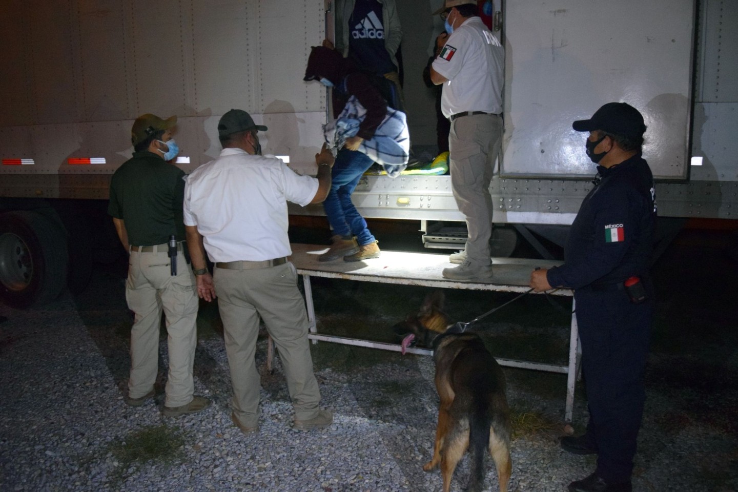 Polizisten und Offiziellle helfen Migranten aus Sattelzügen. Mexikanische Soldaten haben in den Aufliegern dreier Sattelzüge insgesamt 652 mittelamerikanische Migranten in versiegelten Kü...