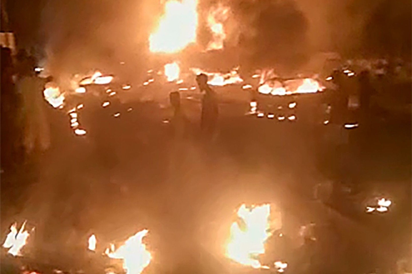 Das aus einem Video stammende Standbild zeigt Personen, die durch brennende Trümmer in Freetown gehen.