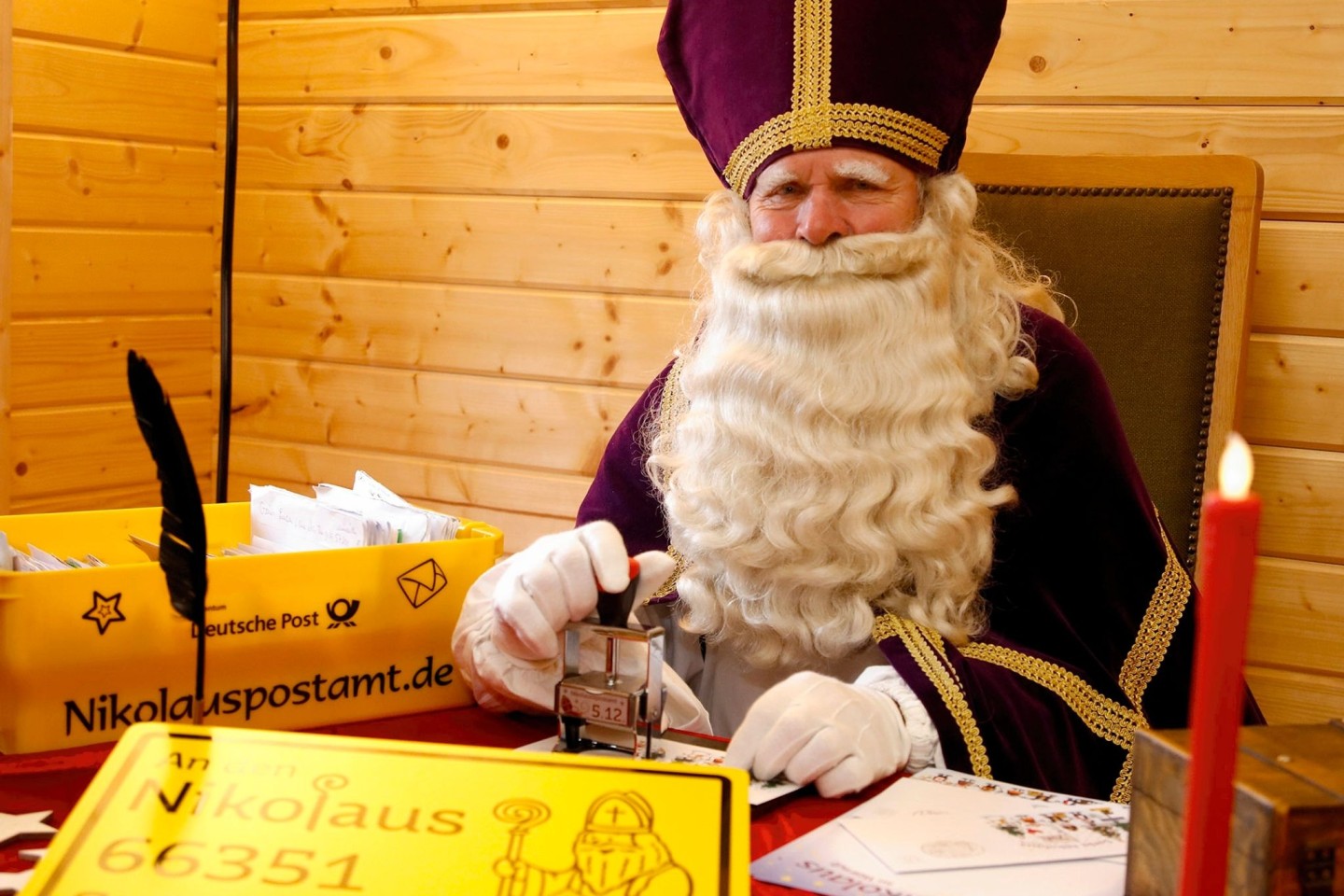 Ein Nikolaus sitzt in seiner Nikolaushütte des Nikolauspostamtes in St. Nikolaus und beantwortet Briefe.