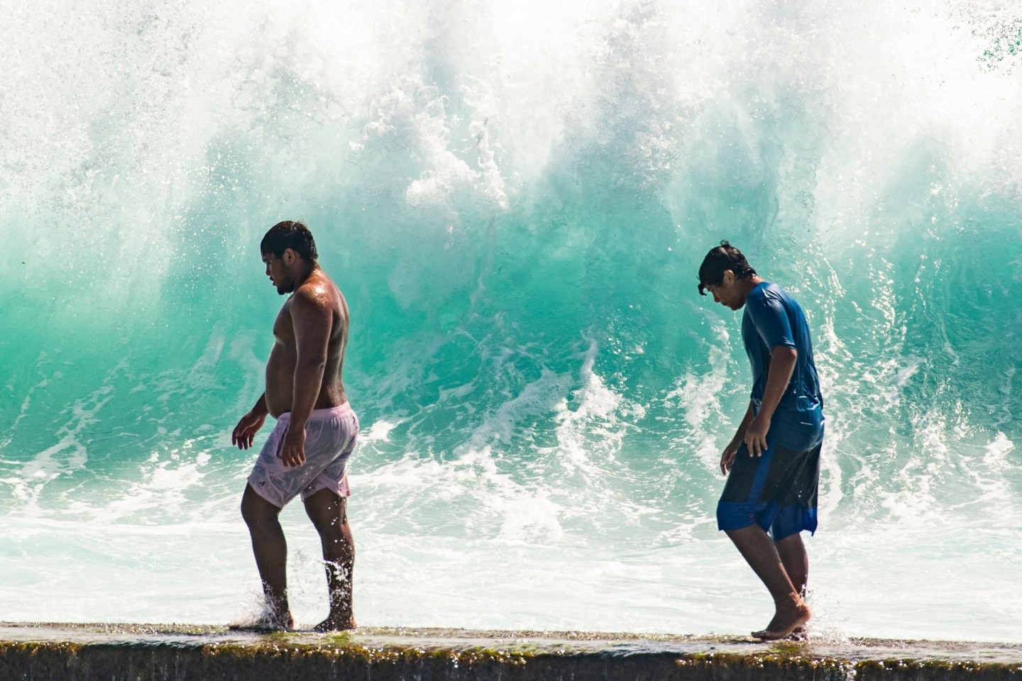 Zwei Männer vor einer hohen Brandung in Waikiki. Massive Wellen trafen an der Südküste Hawaiis auf Land.