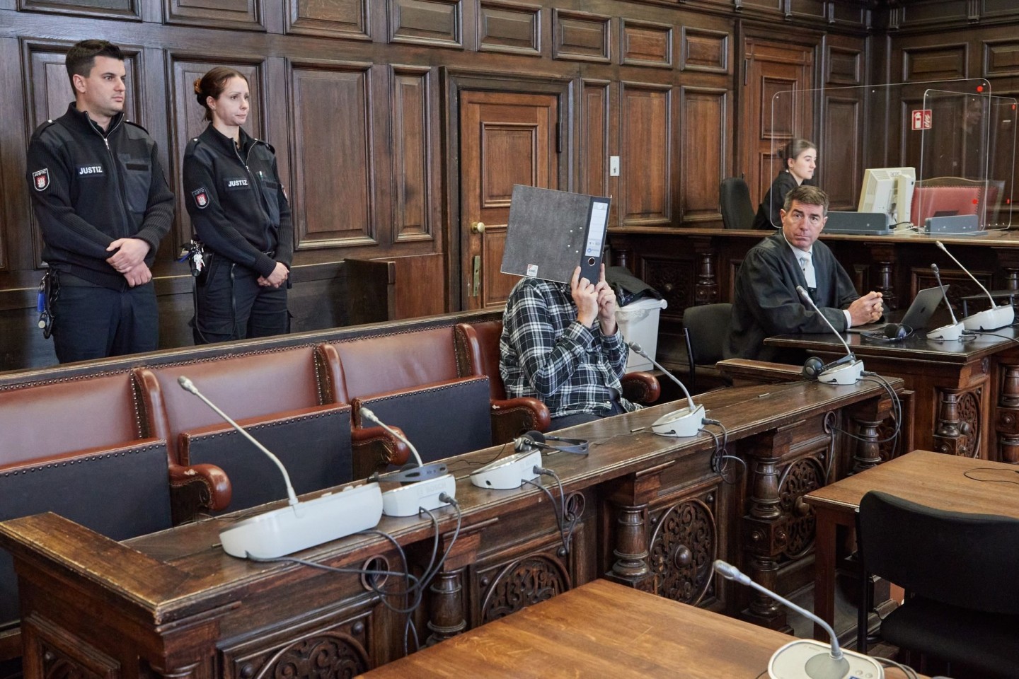 Der Angeklagte (mit Ordner vor dem Gesicht) sitzt im Gerichtssaal neben seinem Anwalt Robert A. Funk (r) kurz vor der Urteilsverkündung.