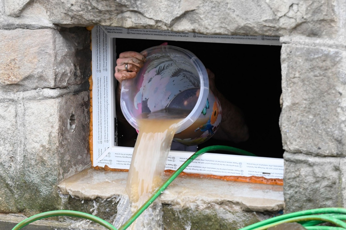 Ein Anwohnerin Hagen schöpft seinen überfluteten Keller leer.