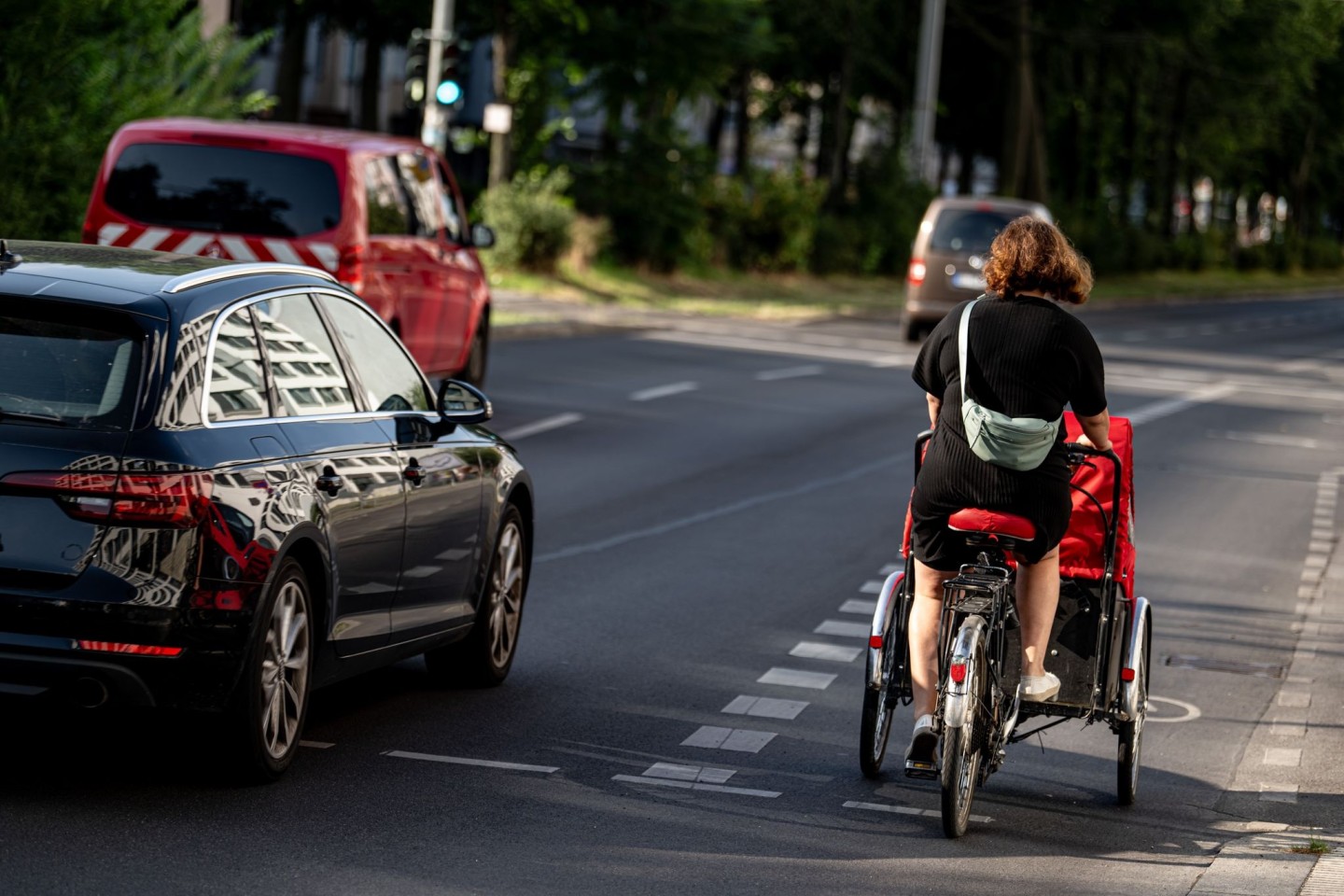 Eine Fahrradfahrerin fährt mit einem Lastenfahrrad. Diese werden oft für den Transport von Kindern benutzt.