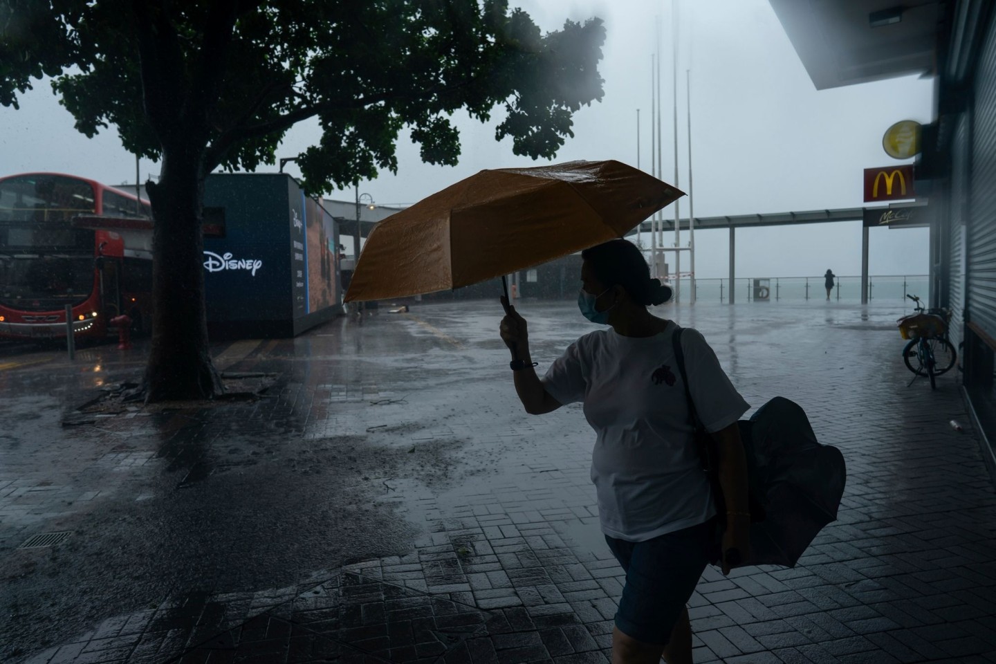 Eine Frau hält einen Regenschirm bei starkem Wind in der Nähe der Promenade von Victoria Habour, als der Tropensturm «Ma-on» an Hongkong vorbeizieht.
