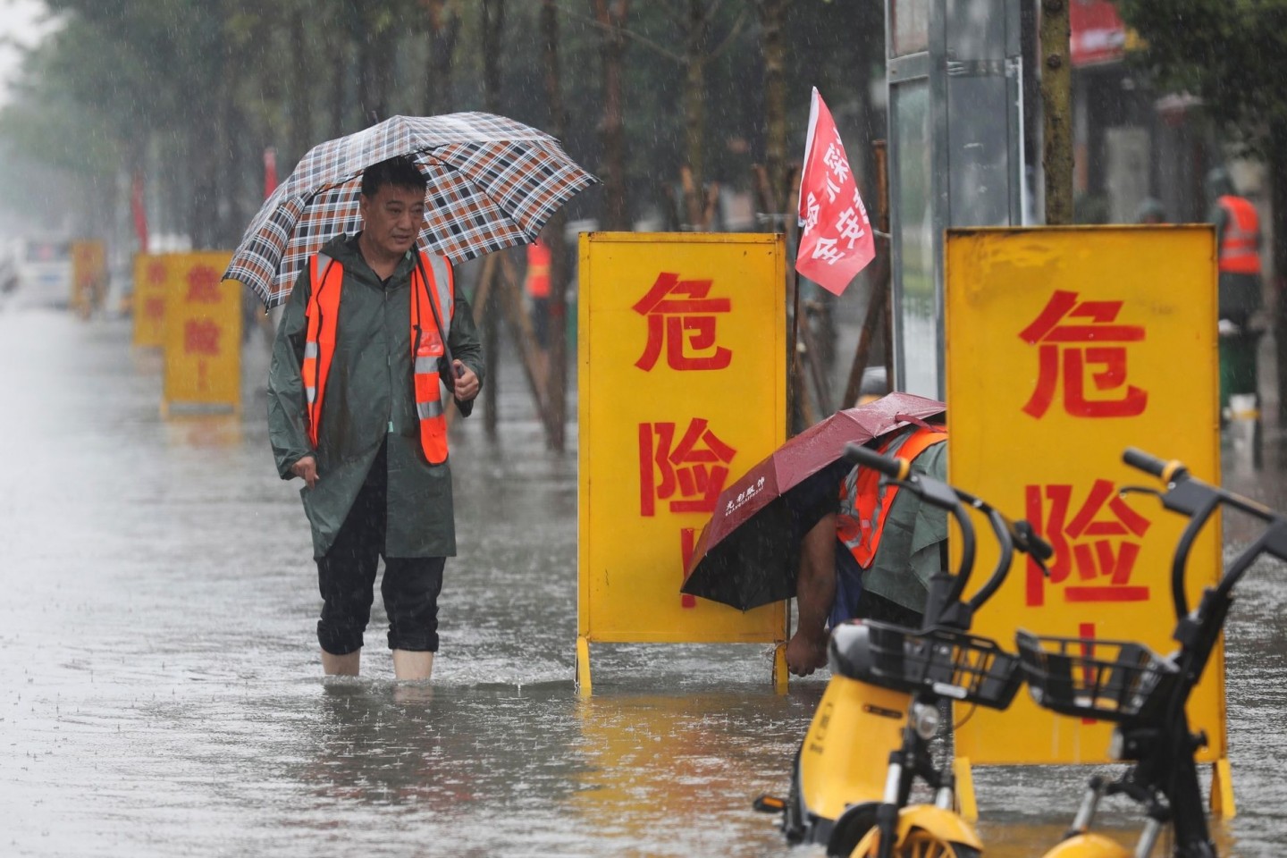 Mitarbeiter stellen Warnschilder auf mit der Aufschrift «Gefahr!» in einem überschwemmten Gebiet im Kreis Wuzhi in der zentralchinesischen Provinz Henan.