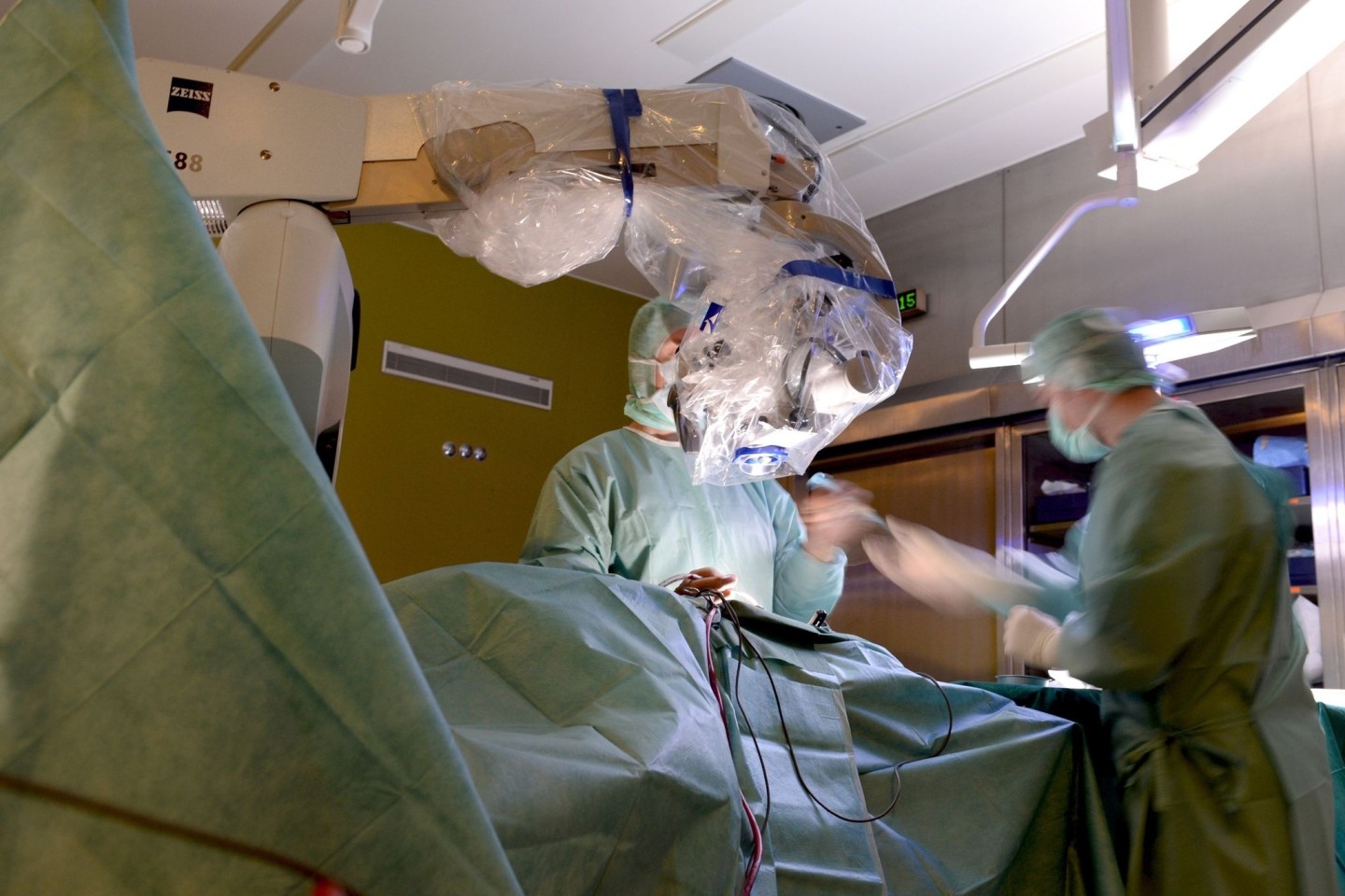 Ein Mediziner operiert in einer Klinik in Baden-Württemberg während einer Bandscheibenoperation an der Lendenwirbelsäule mit einem Mikroskop.