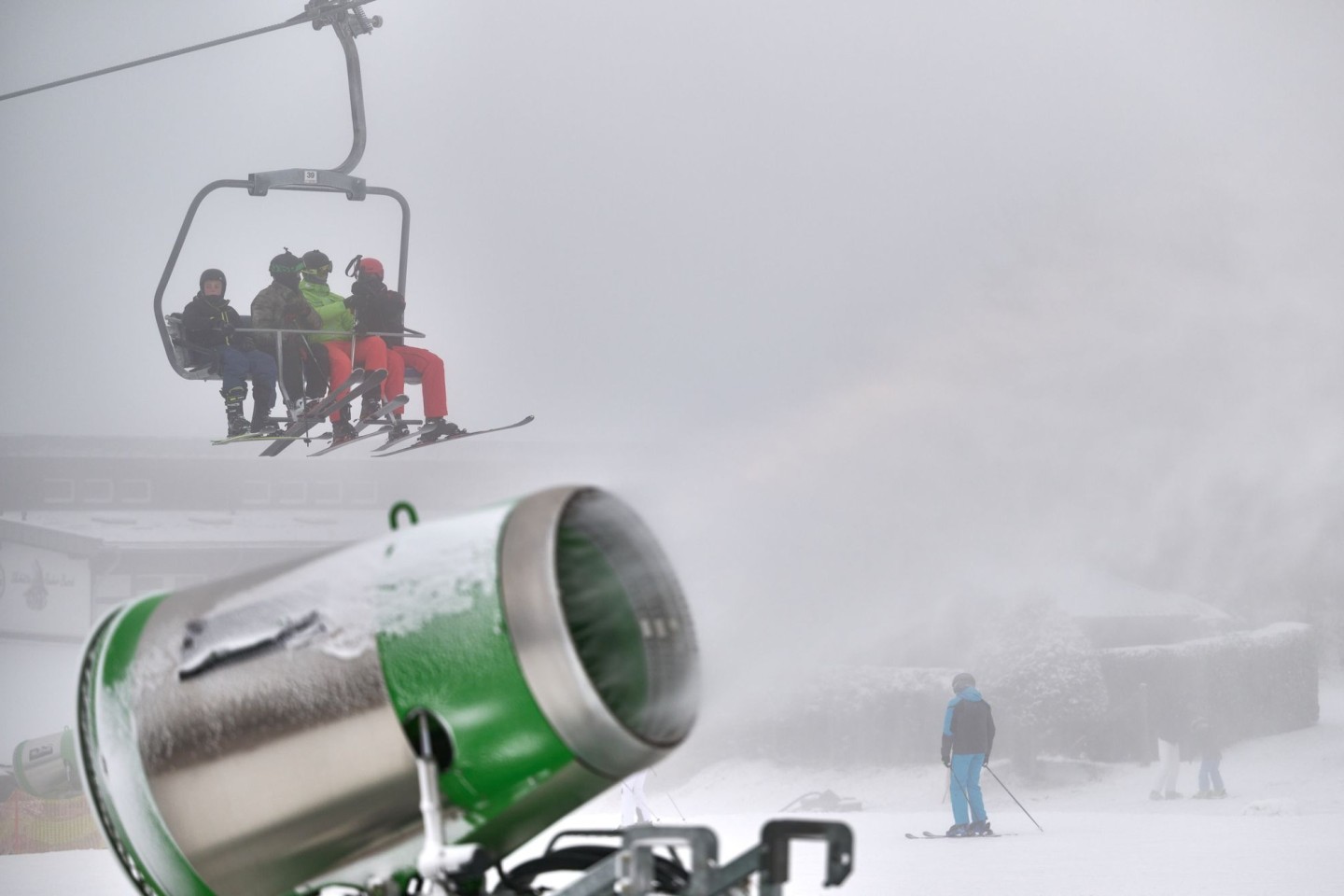 Wintersportler gondeln über einer künstlich beschneiten Piste an der Remmerswiese nach oben.
