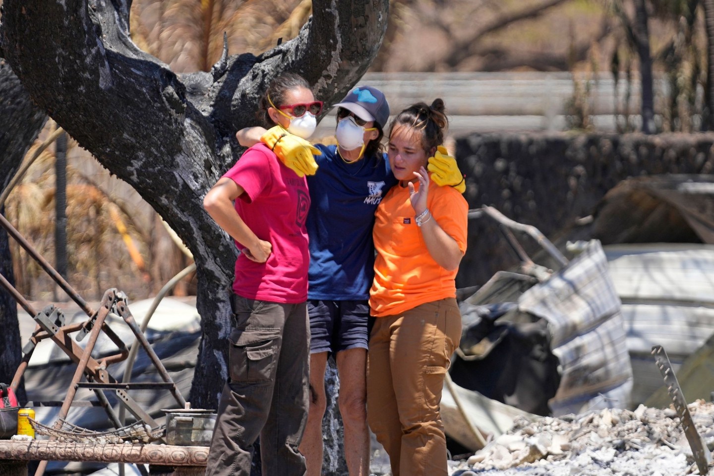 Frauen umarmen sich in den Trümmern eines vom Feuer zerstörten Hauses in Lahaina auf Hawaii.