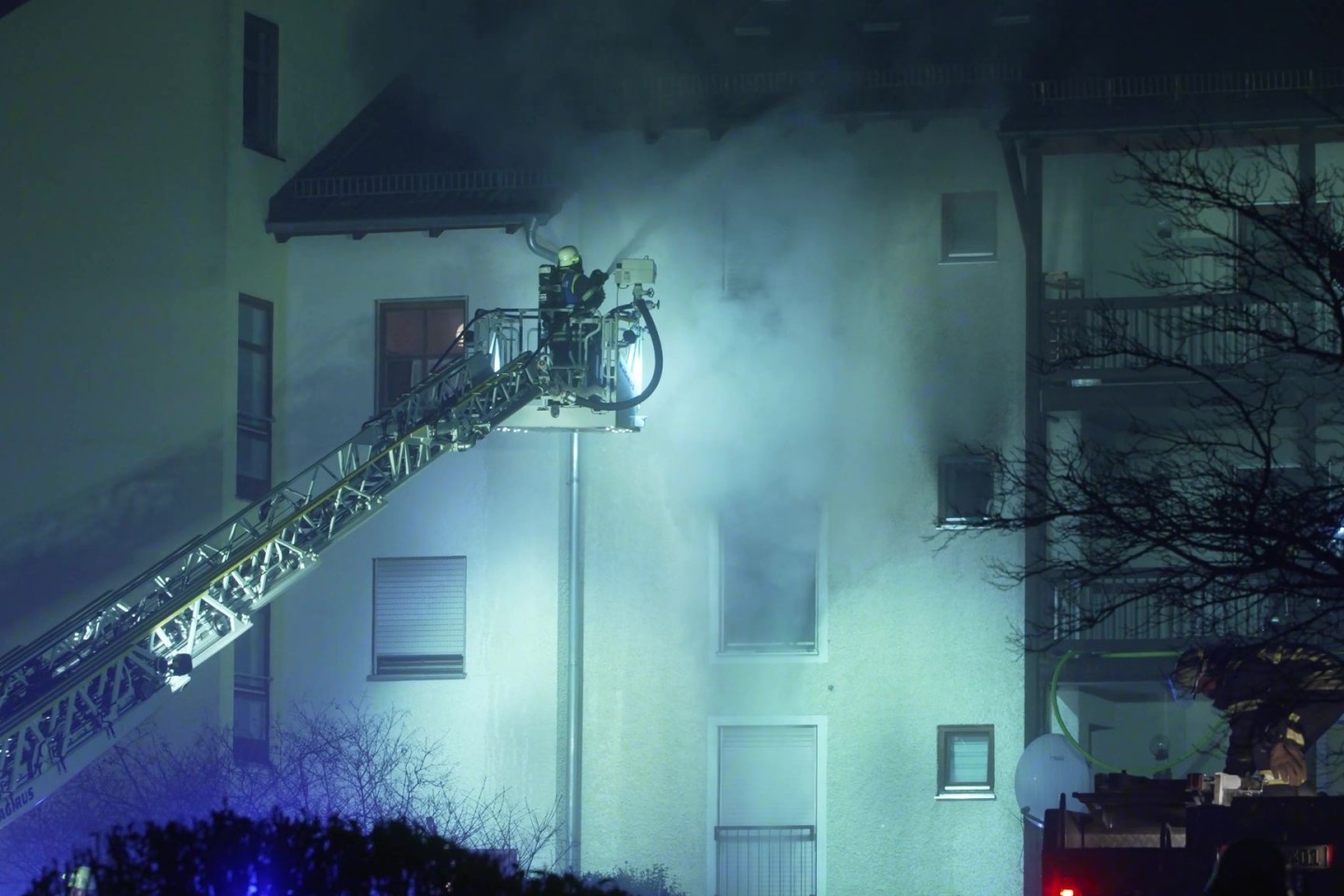 Feuerwehrleute sind bei einem Brand in einem Mehrfamilienwohnhaus in Bayern im Einsatz.